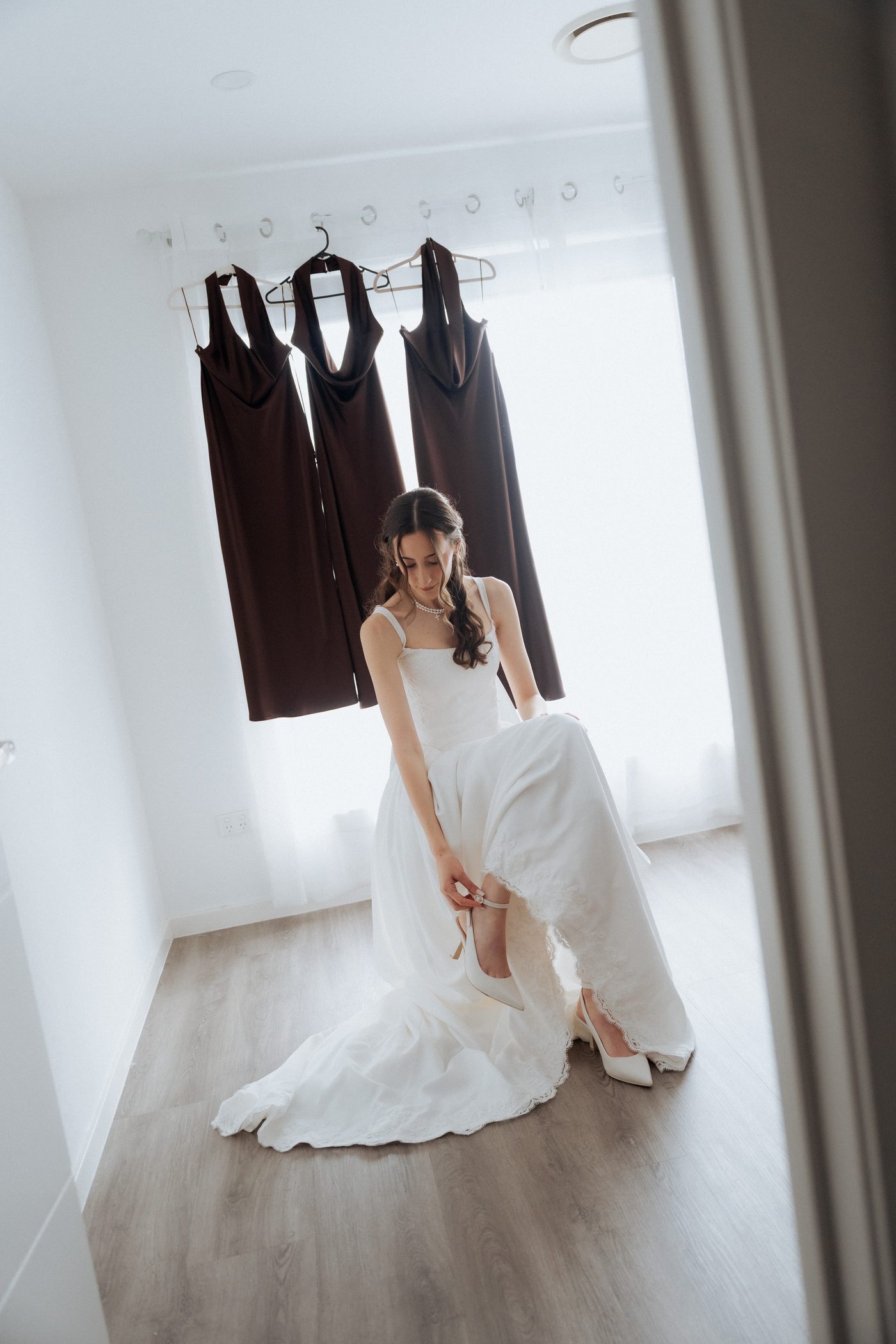 Bride Ashleigh putting on her shoes with bridesmaids in chocolate dresses