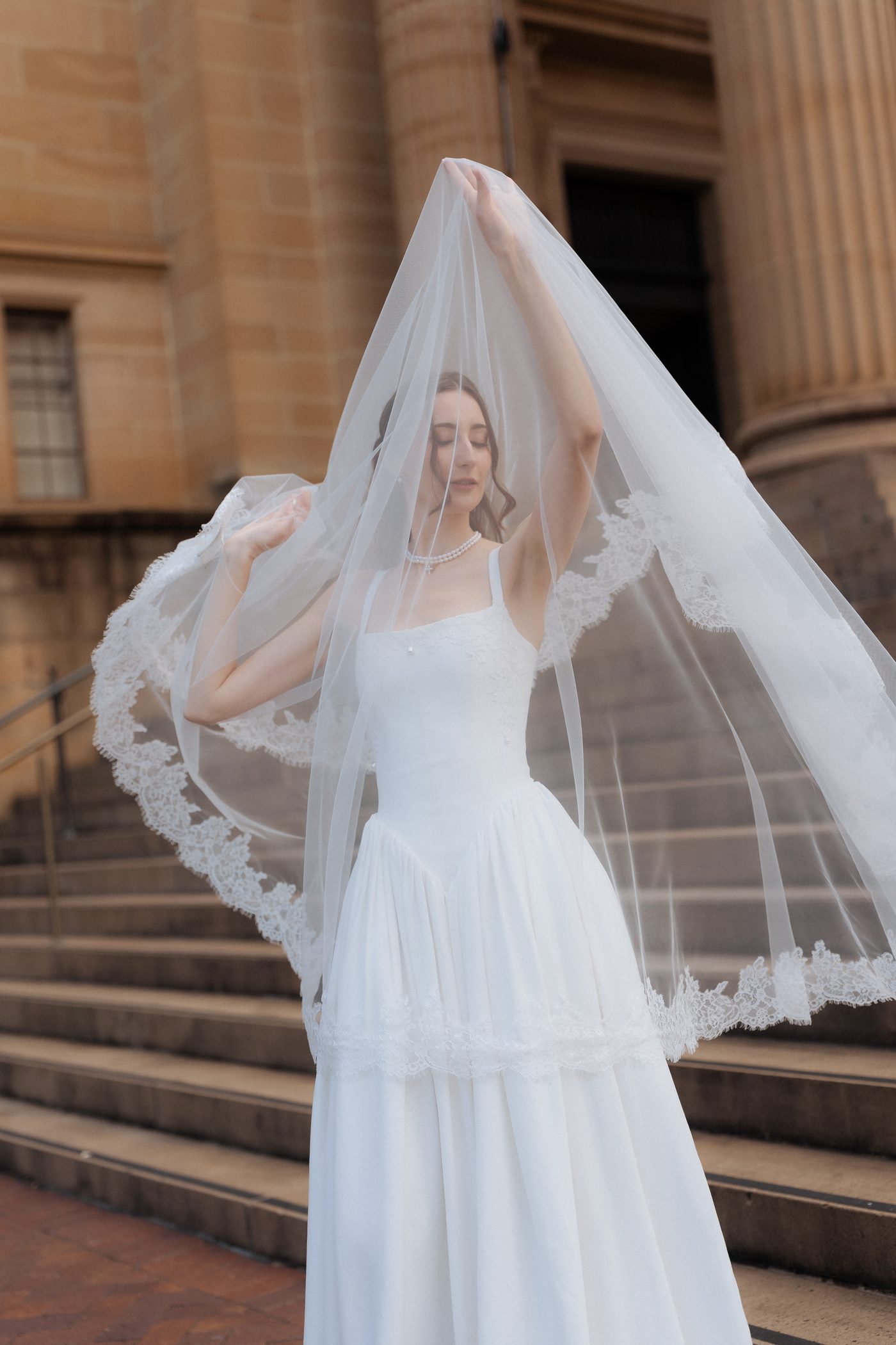 Bride's veil floating dramatically on the sandstone steps of the State Library of NSW